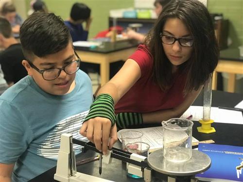 students doing a science experiment with a scale
