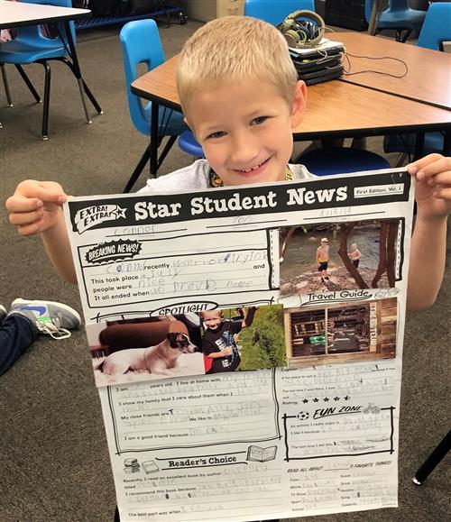 a student shows off a newspaper reporting project